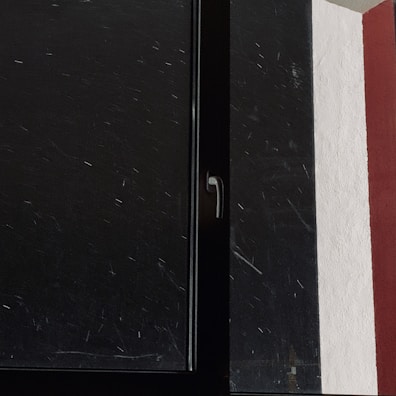 Close-up of painter’s brush adding red paint to interior window frame.