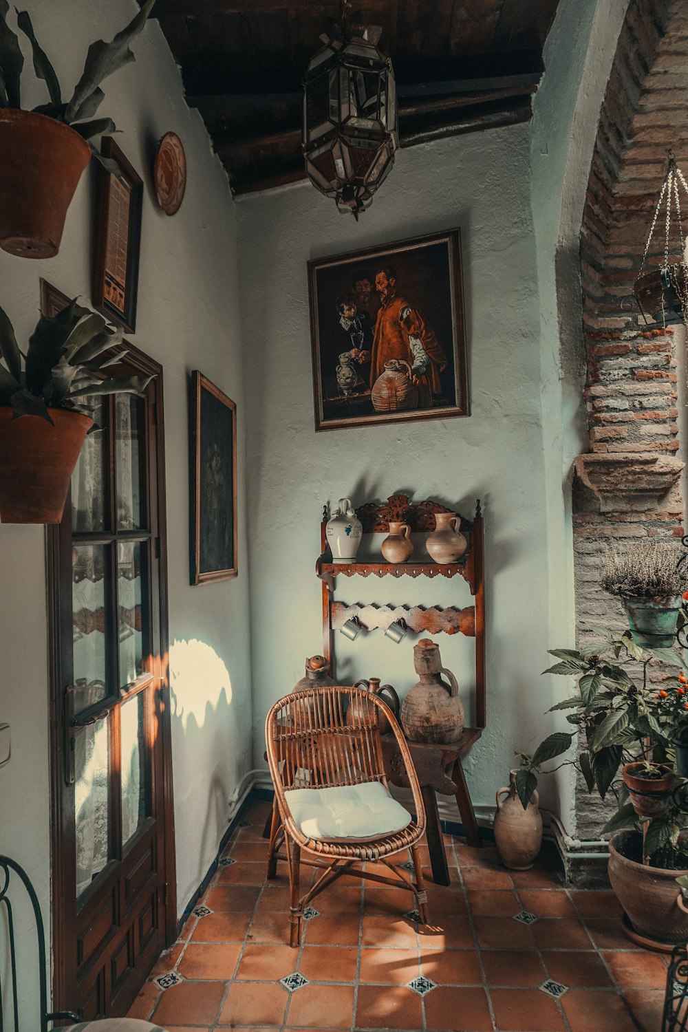 a room with a chair, potted plants and pictures on the wall