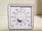 A square analog timer with a white face, black numbers, and a central knob. The timer is marked with numbers at five-minute intervals, and a red indicator shows the time set to 30 minutes.