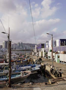 A bustling dock where frozen fish containers are being loaded onto a ship under clear skies.