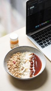 Close-up of a journal with a pen, next to a healthy breakfast bowl.