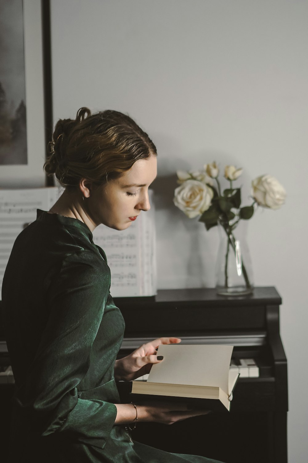 a woman sitting at a piano reading a book