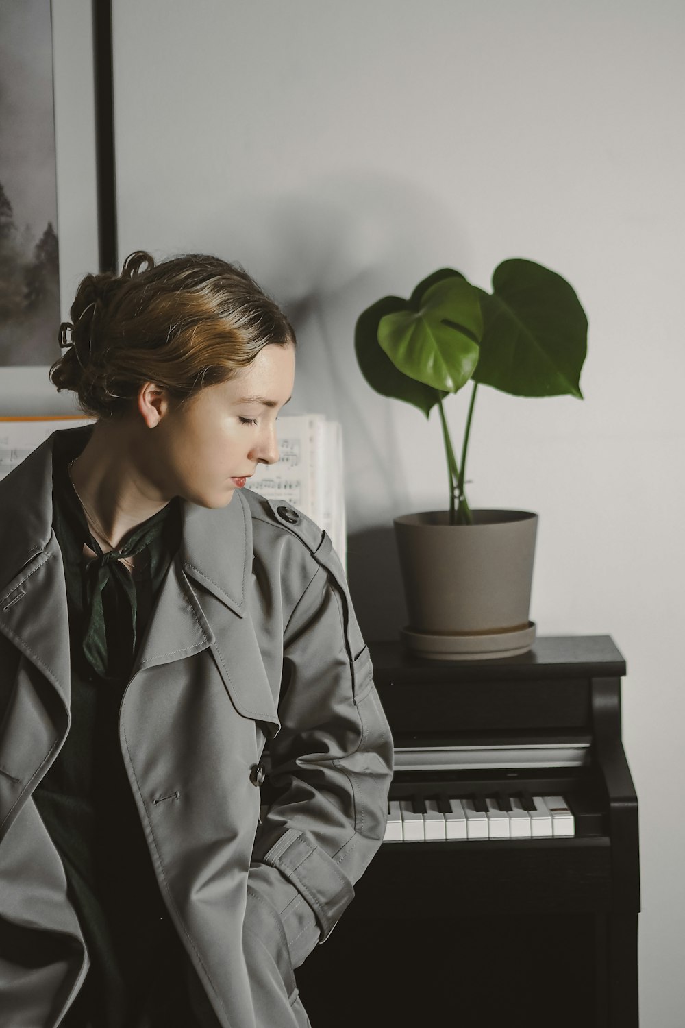 a woman in a trench coat sitting at a piano