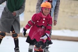 A joyful child learning to skate with protective gear, smiling widely on a smooth skating rink.