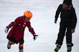 Children learning to balance on skates with joyful expressions in an outdoor class