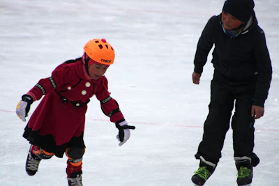 Children learning to balance on skates with joyful expressions in an outdoor class