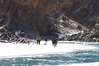 A group of hikers crossing a sparkling river in an offbeat wilderness location.