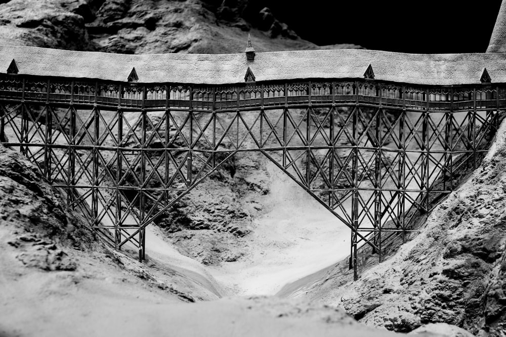 a black and white photo of a bridge in the mountains