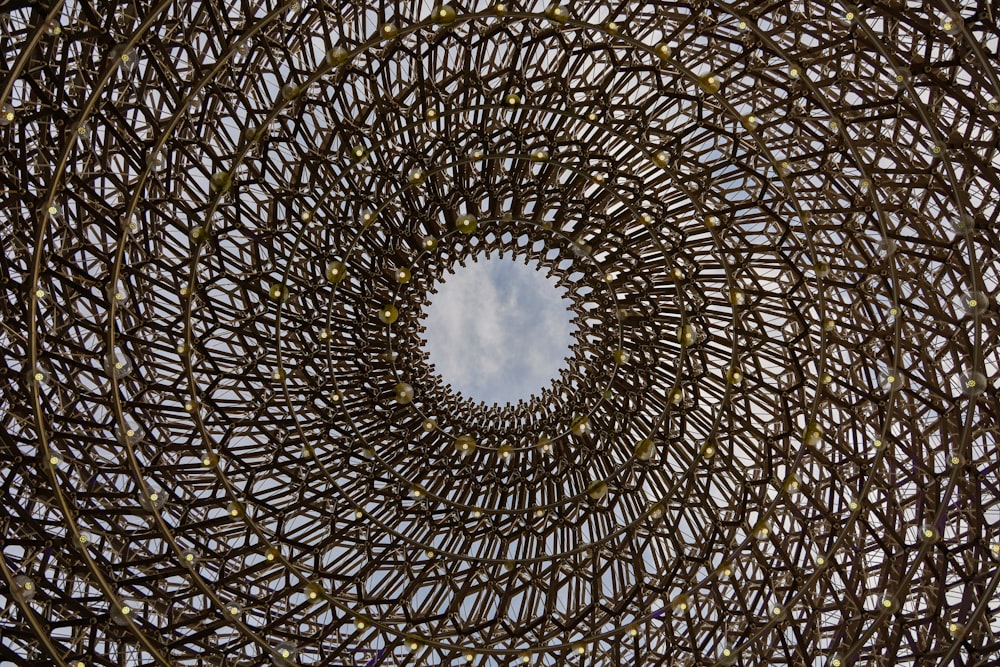 a circular sculpture made of branches with a sky in the background