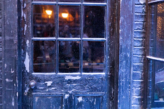 A craftsman fitting a stylish wooden door in a cozy Queens neighborhood home during daylight.