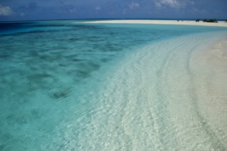 a sandy beach with blue water and white sand