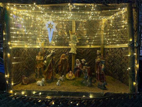 Children playing near a beautifully decorated nativity scene under soft evening light.