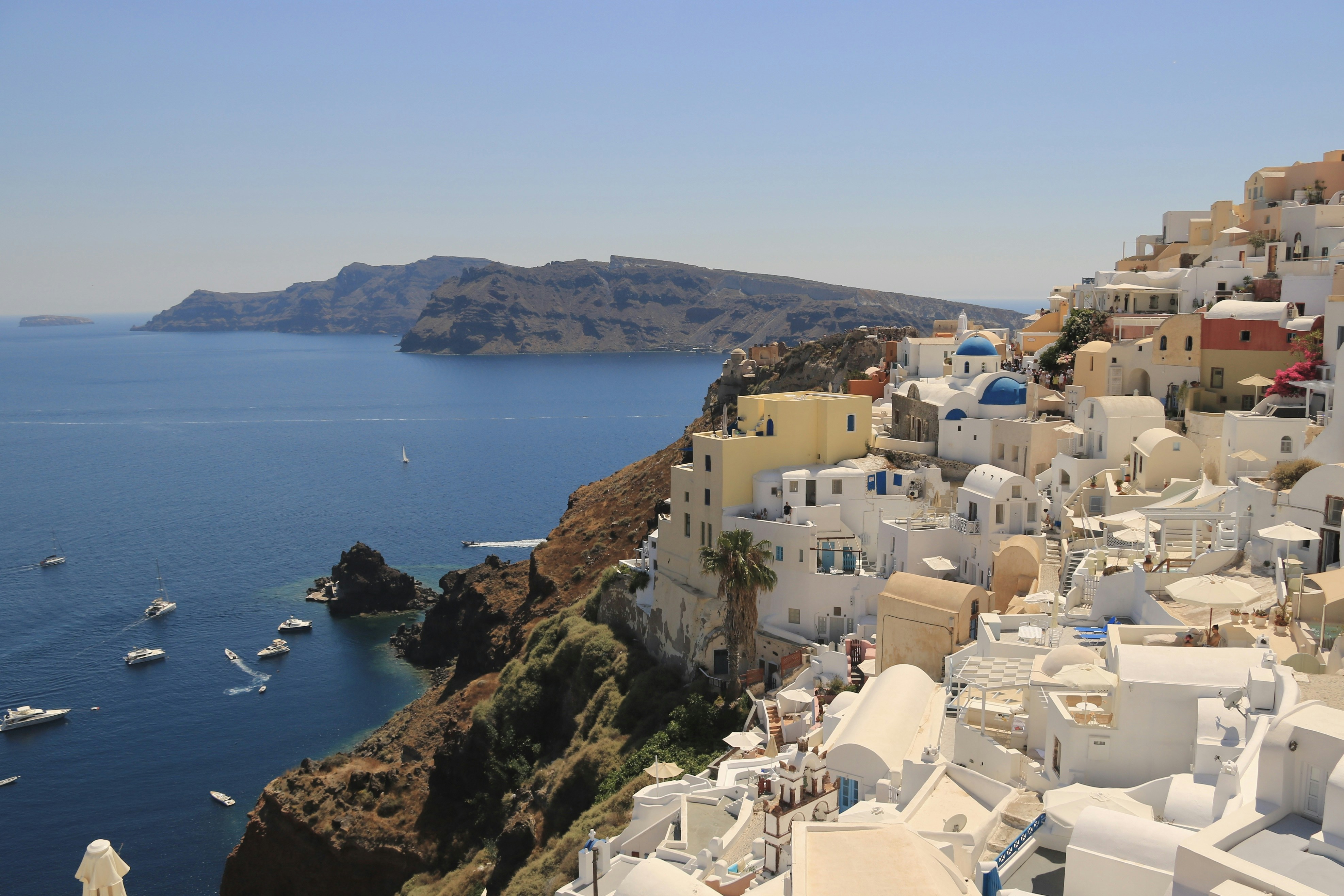a view of a village on a cliff overlooking the ocean, Santorini🇬🇷
