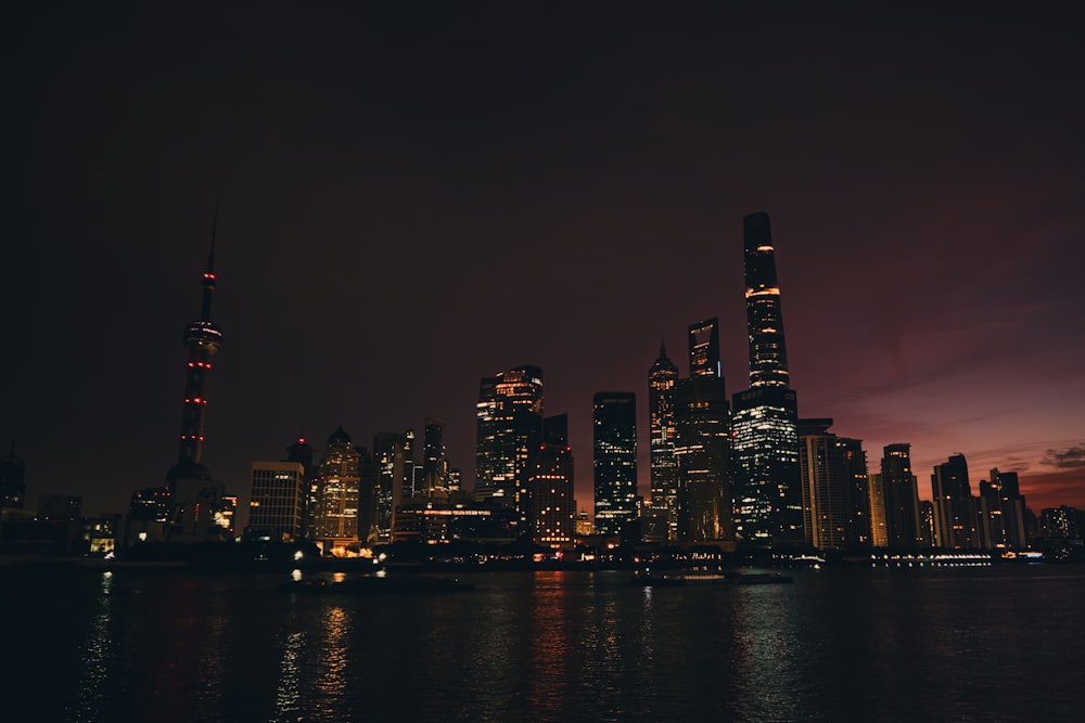 a city skyline at night with lights reflecting off the water