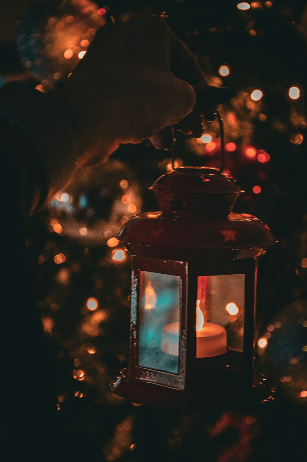 a person holding a lit candle in front of a christmas tree