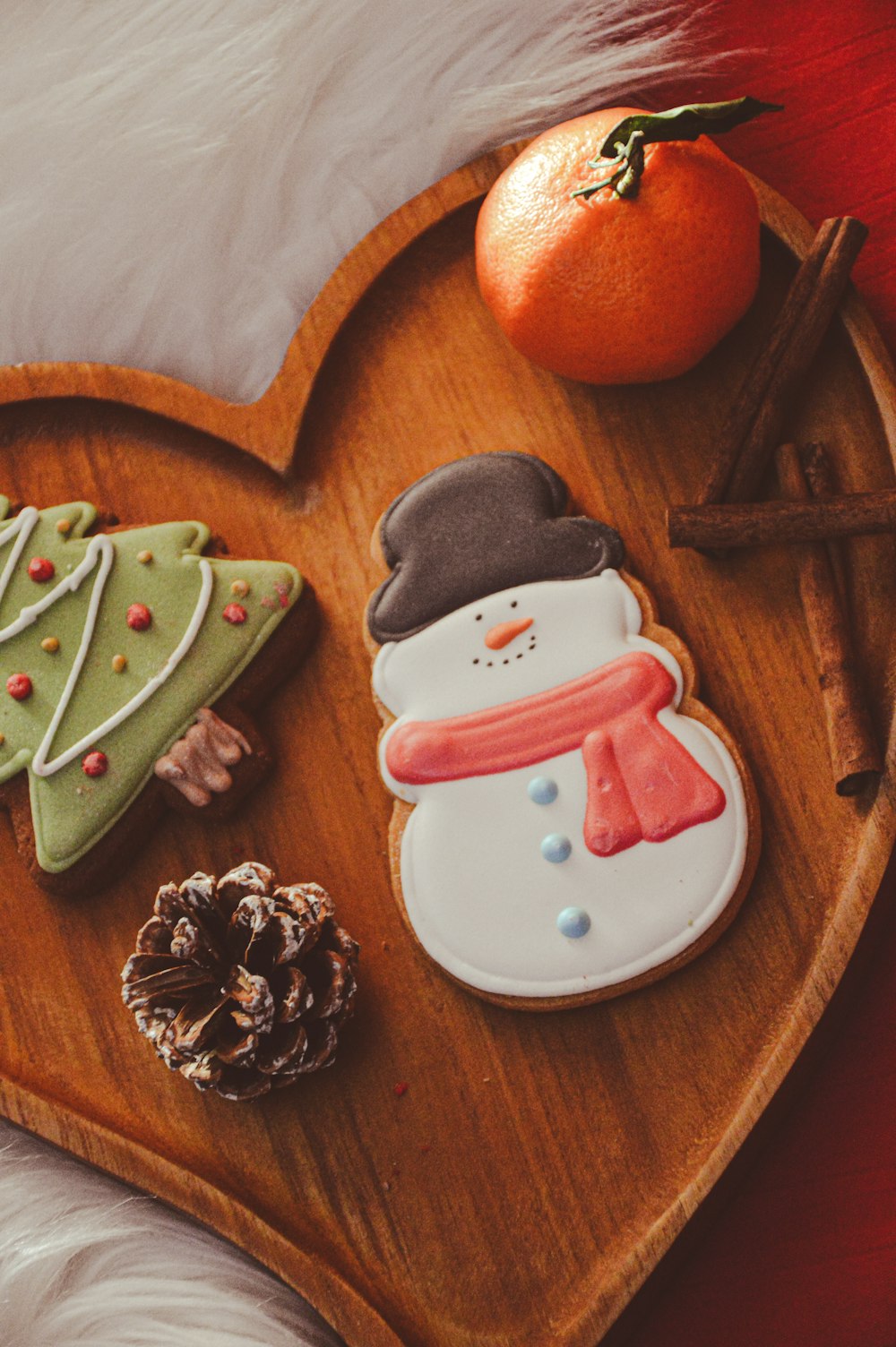 a heart shaped wooden tray with cookies and an orange