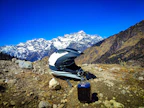 Helmet and gloves laid out on a wooden table with mountain background