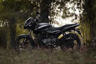 a black motorcycle parked in the middle of a forest