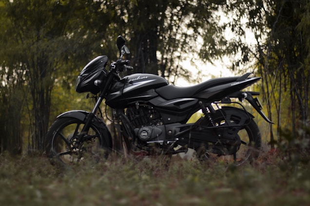 a black motorcycle parked in the middle of a forest