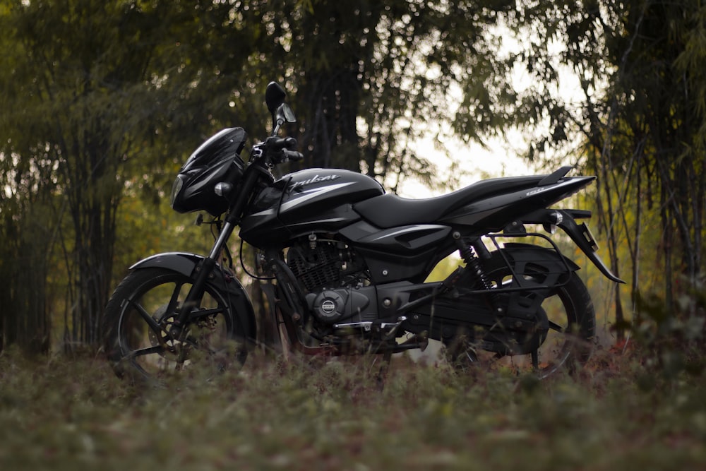 a black motorcycle parked in the middle of a forest