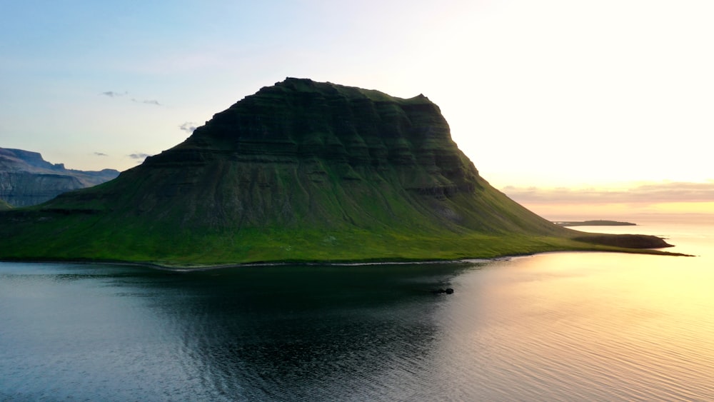 a large green mountain sitting on top of a body of water