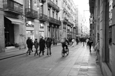 a group of people walking down a street next to tall buildings