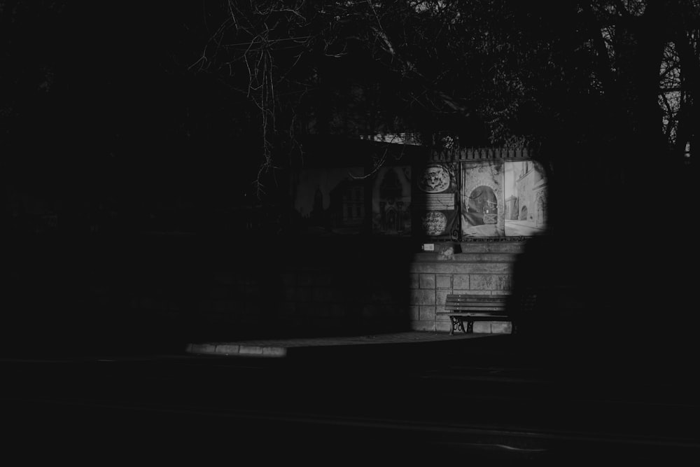 a black and white photo of a bench in the dark