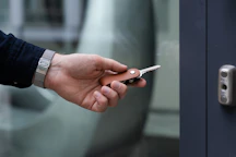 A close-up of hands exchanging keys in front of a newly renovated property.