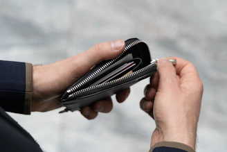 A person holding an open wallet filled with cards and cash, smiling in a cozy café setting.