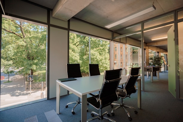 A private office with a desk, ergonomic chair, and large windows.
