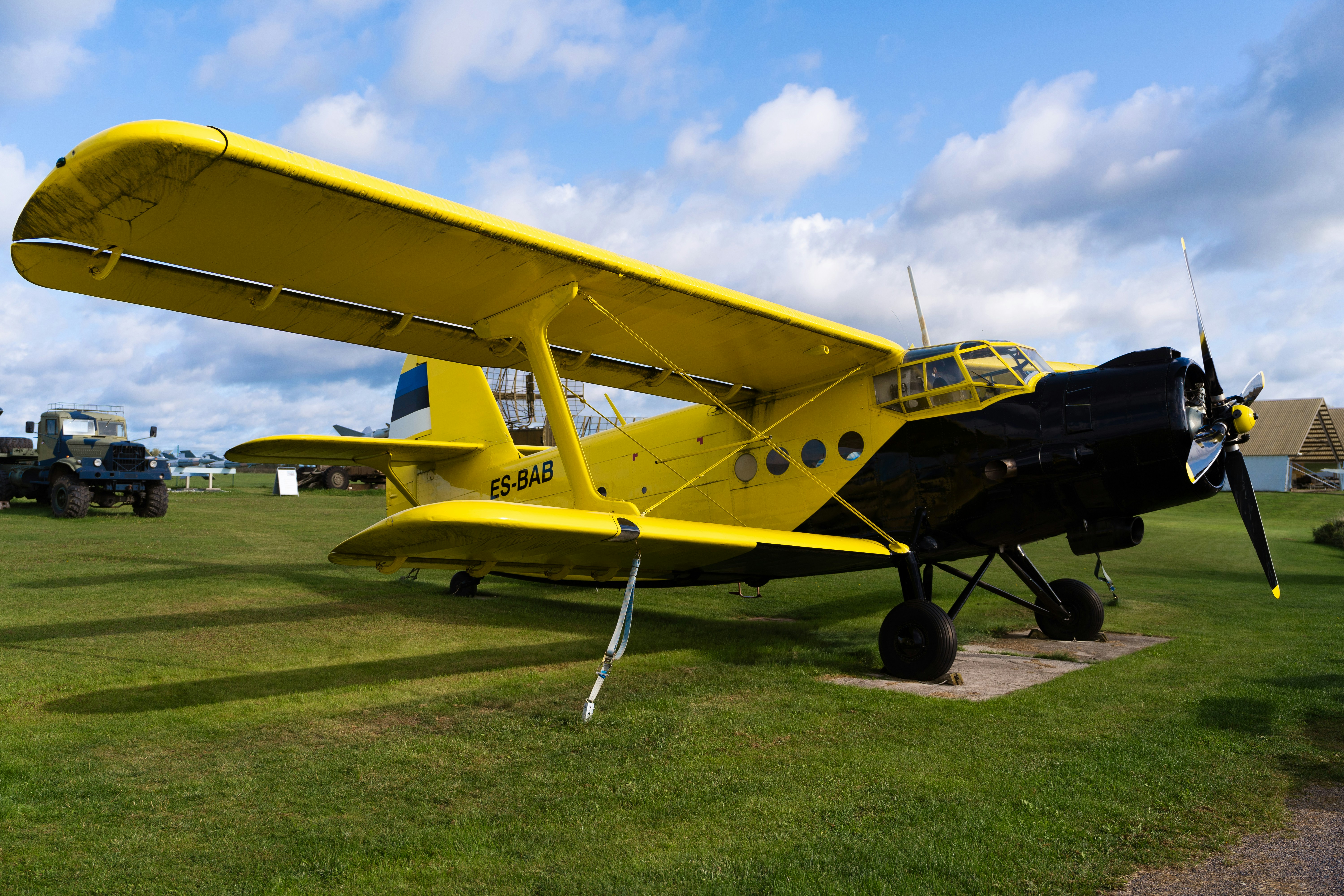 a yellow airplane sitting on top of a lush green field, Photo of a yellow plane with a propeller.