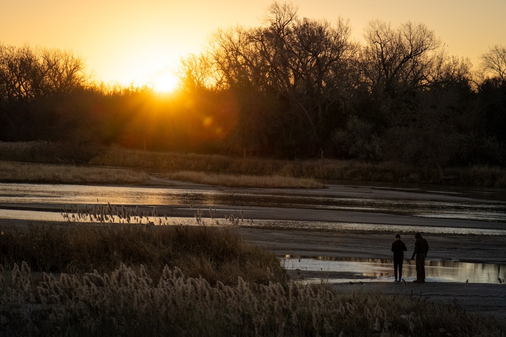 a couple of people standing next to each other near a river