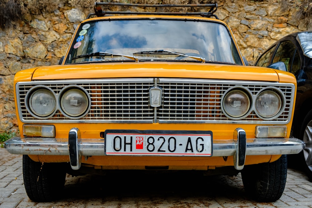 a yellow car parked in front of a stone wall