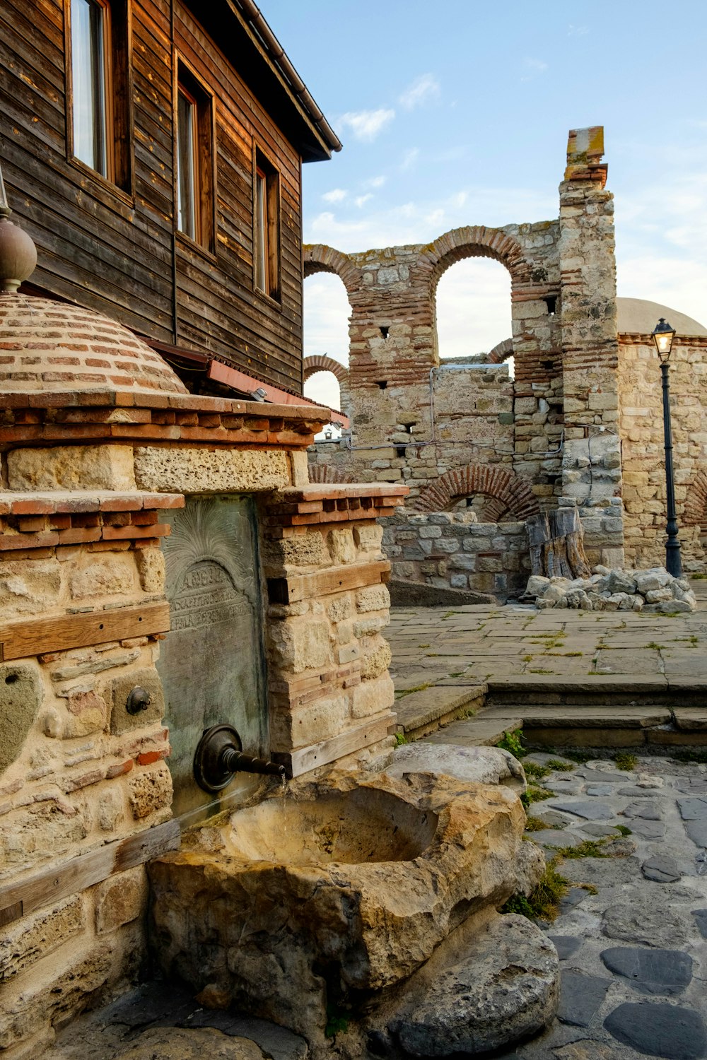 a stone fountain in front of a brick building