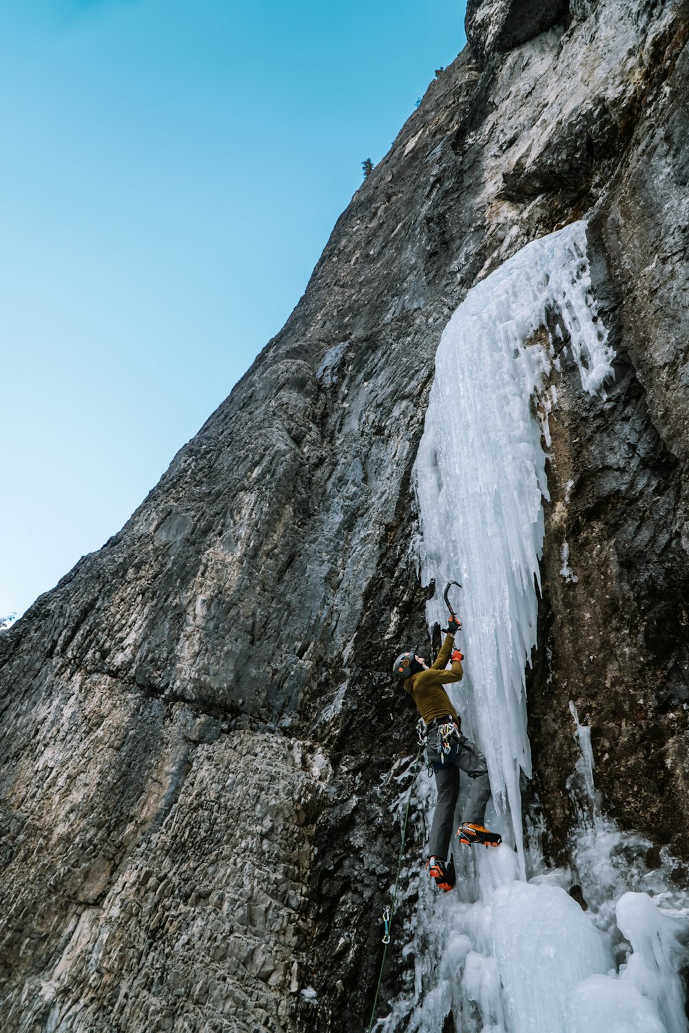 a man climbing up the side of a snow covered mountain