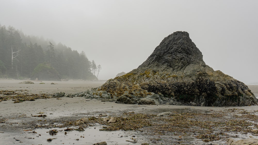 una gran roca sentada en la parte superior de una playa de arena