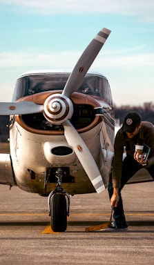 A friendly technician discussing aircraft maintenance details with a client beside a small airplane.