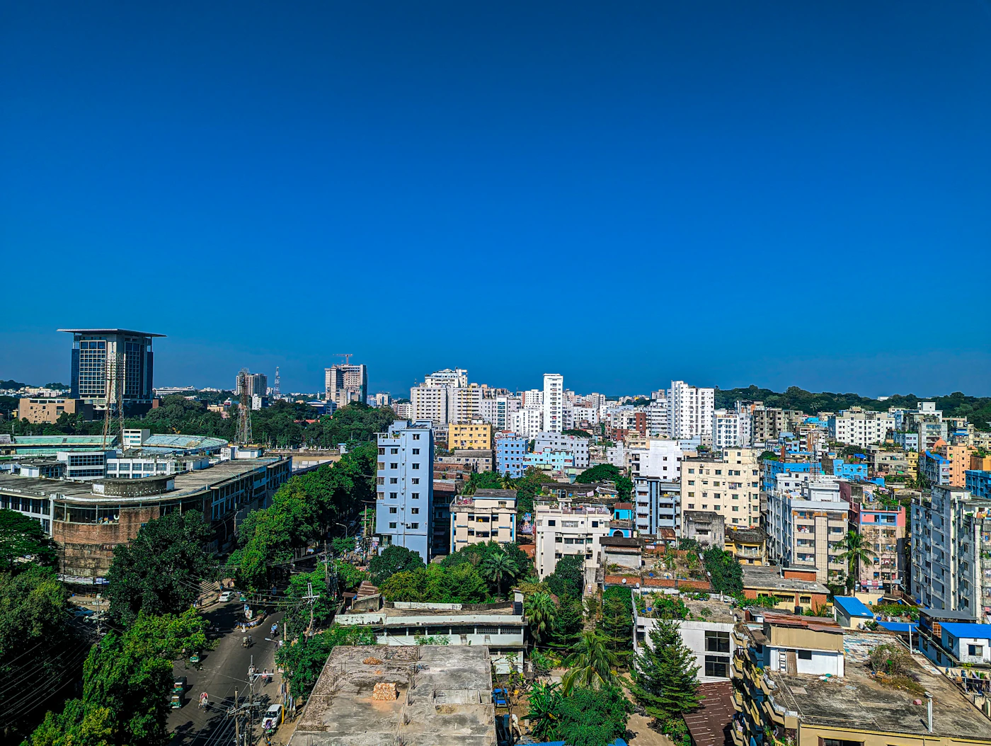 Aerial view of a dense city skyline with green hills on the horizon