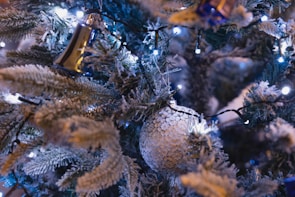 Close-up of a snowy white Christmas tree adorned with delicate fairy lights and rustic wooden decorations.