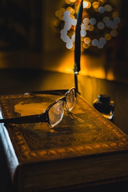 An old-fashioned quill pen resting beside a leather-bound historical romance novel.