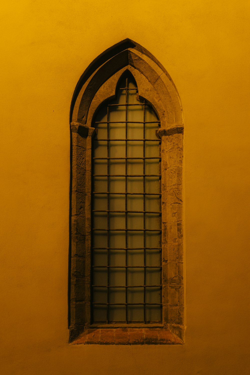 a window in a yellow wall with a window pane