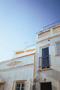 A freshly painted luxury home's exterior with crisp white walls and gold trim under bright sunlight.