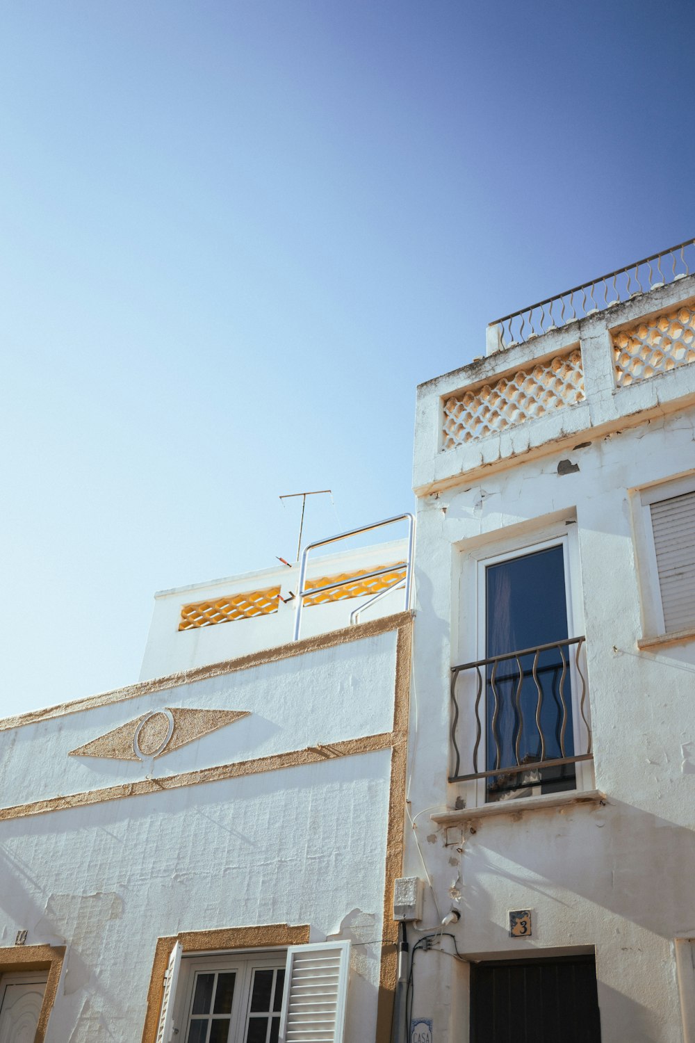 a tall white building with a balcony and a door