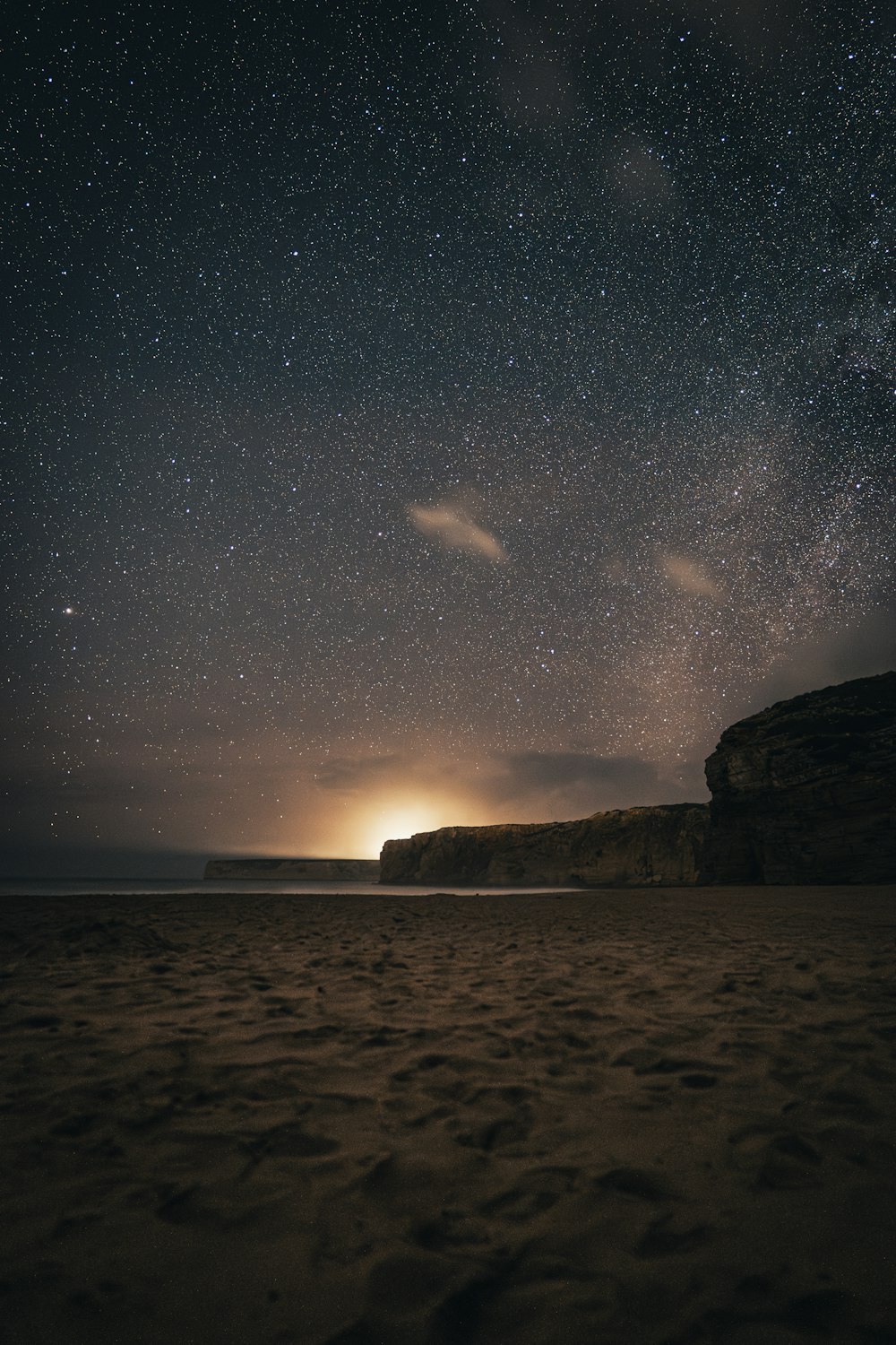 the night sky with stars above a beach