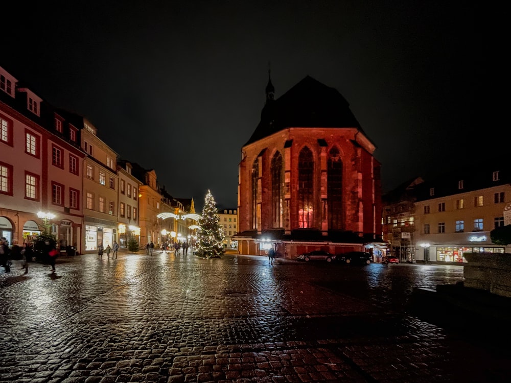 a city street at night with a lit christmas tree