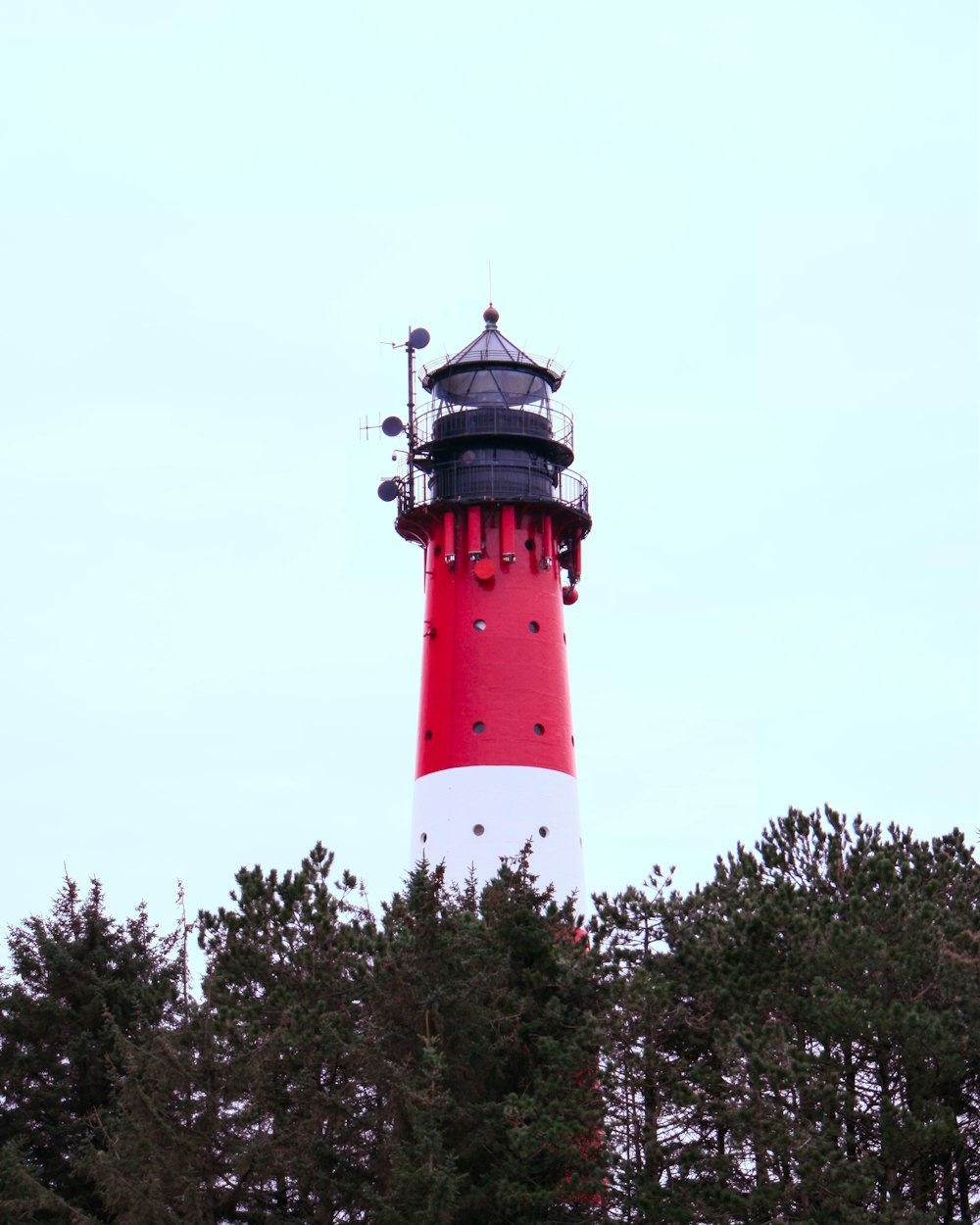 a red and white lighthouse surrounded by trees