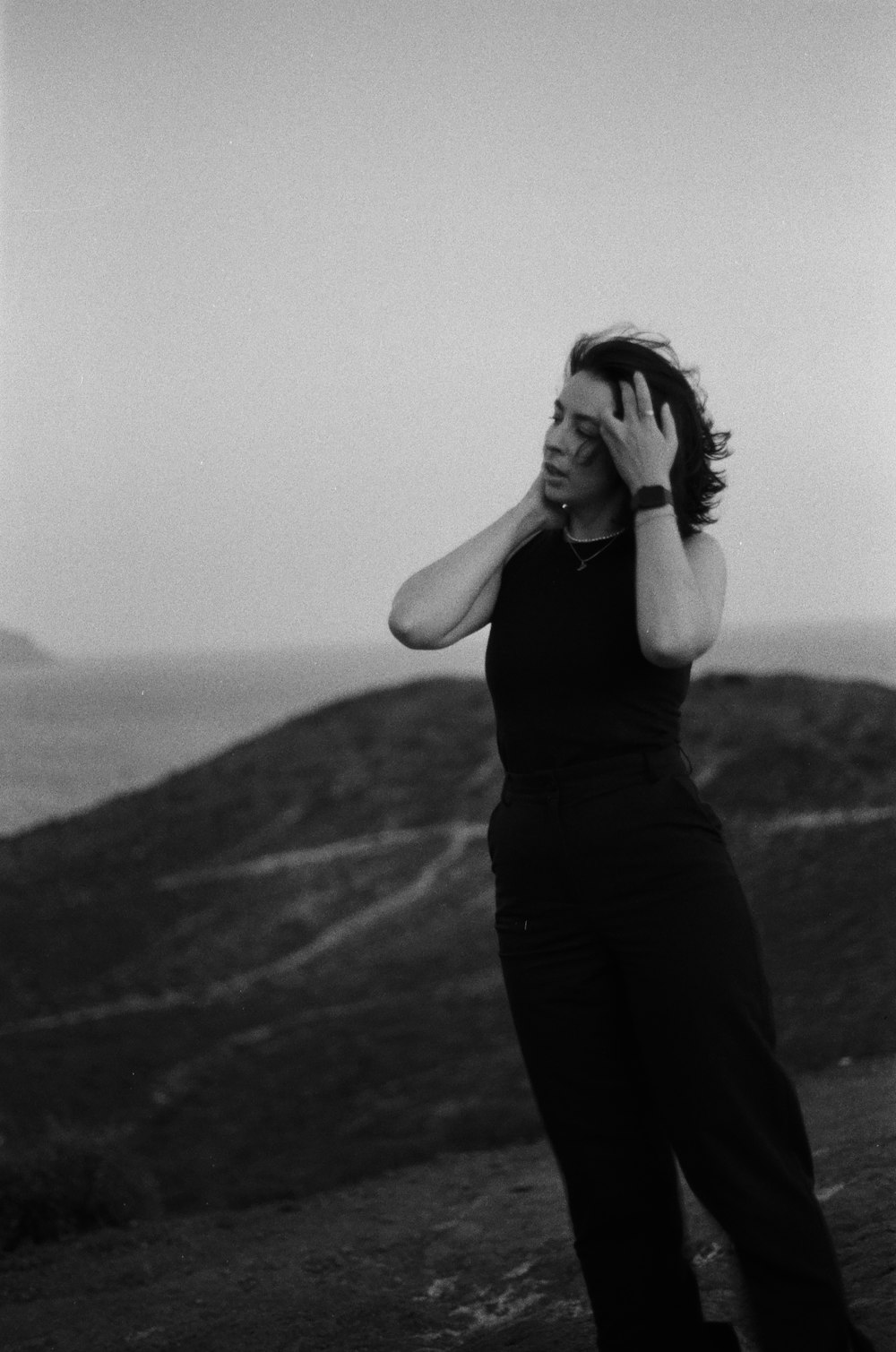 a woman standing on top of a lush green hillside