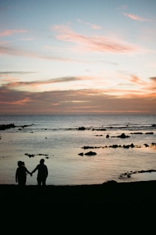 A serene couple holding hands beneath a soft glowing sunset signifying new beginnings.