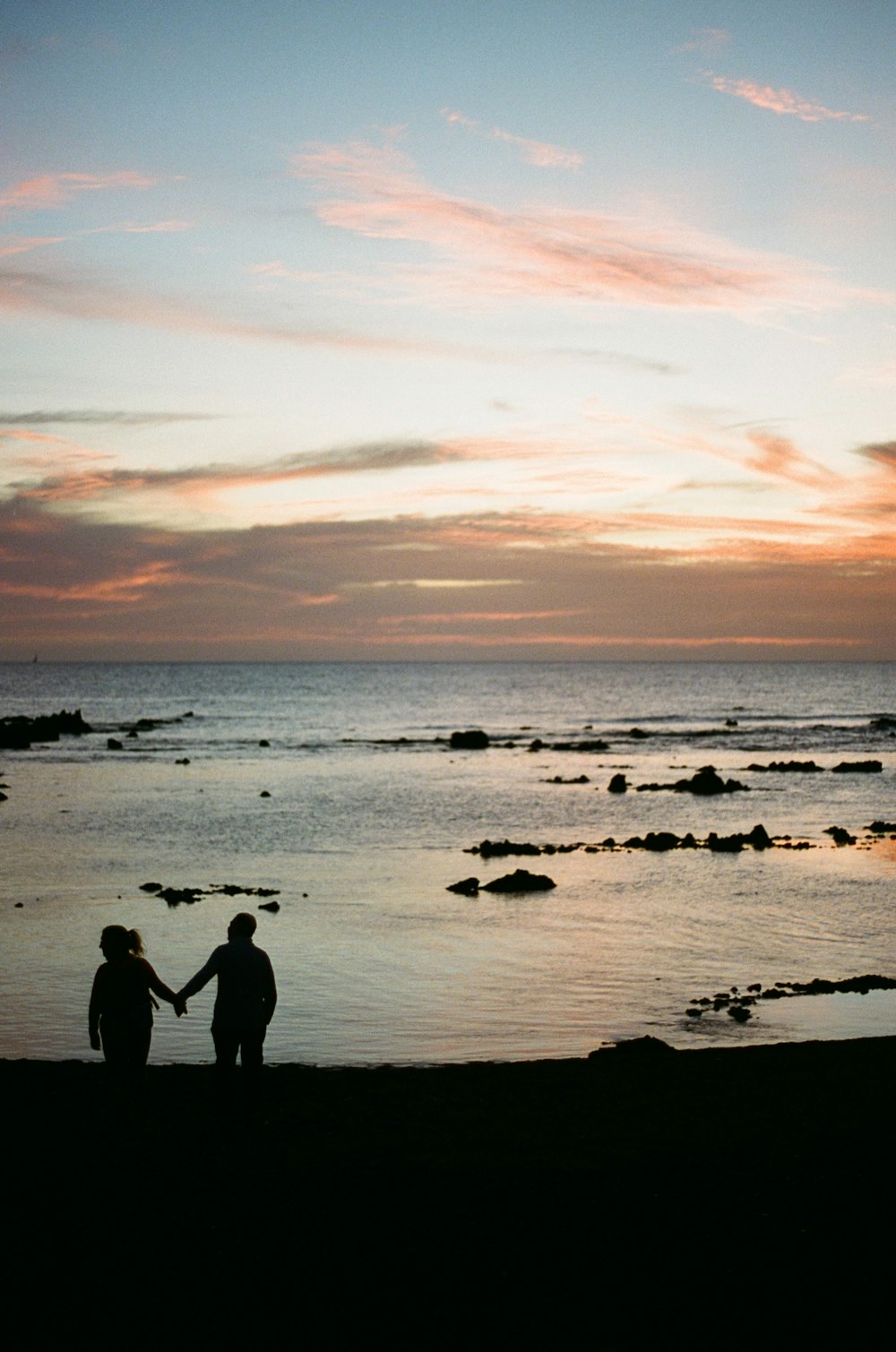 a couple of people standing on top of a beach