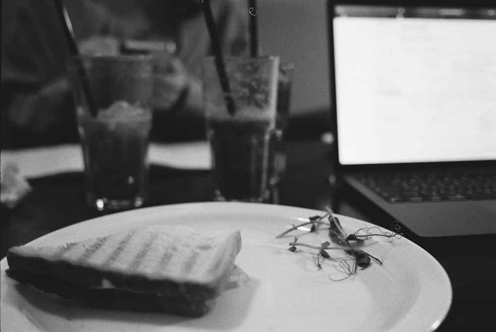 a white plate topped with a sandwich next to a laptop